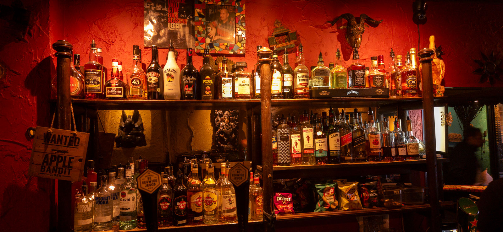 The back bar: shelves of spirits under a red wall