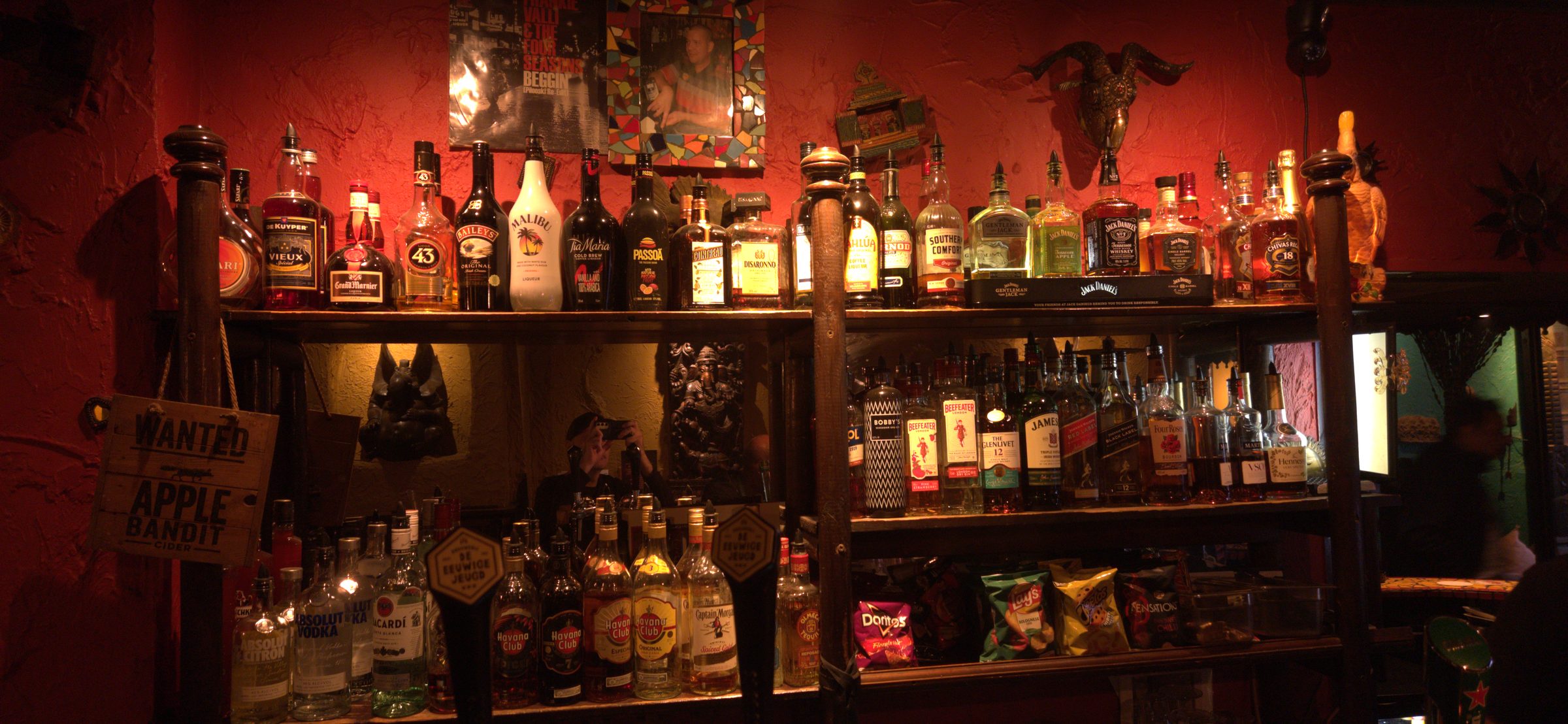 The back bar: shelves of spirits under a red wall